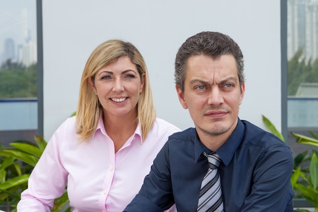 Dos hombres de negocios masculinos y femeninos contentos de mediana edad al aire libre.