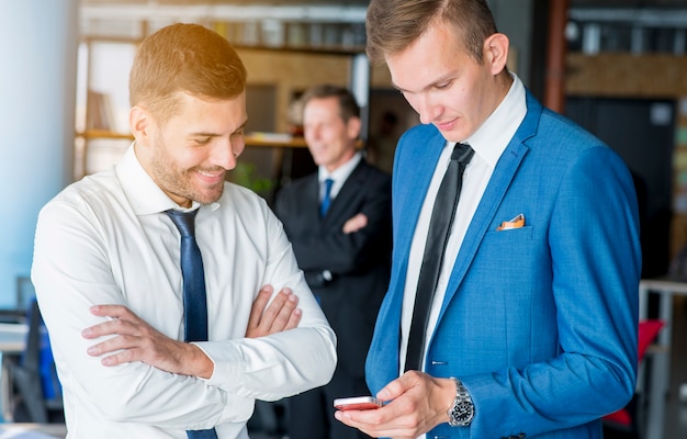 Dos hombres de negocios mirando la pantalla del teléfono móvil