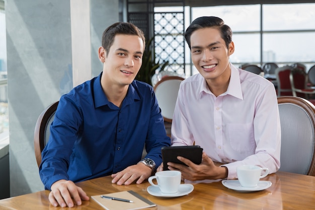 Dos hombres de negocios sonriente que trabaja en la computadora de la tableta