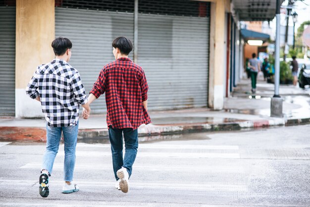 Dos hombres que se aman se dan la mano y caminan juntos.