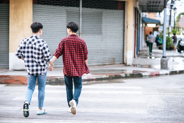 Dos hombres que se aman se dan la mano y caminan juntos.