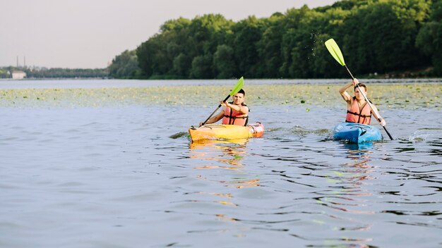 Dos hombres rema en kayak en el lago tranquilo