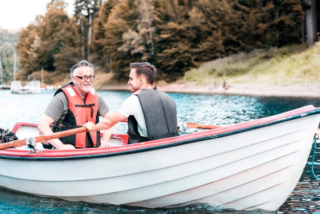 Dos hombres remando en un bote en el lago tranquilo