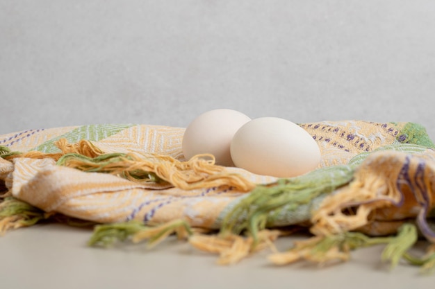 Foto gratuita dos huevos blancos de gallina fresca sobre mantel.