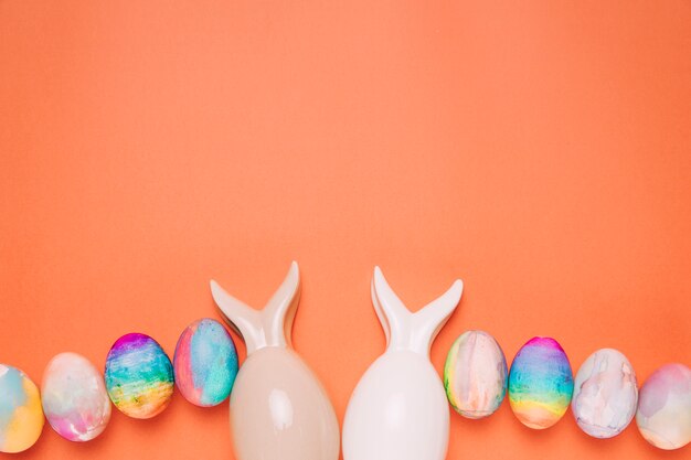 Dos huevos de Pascua con orejas de conejo sobre fondo naranja