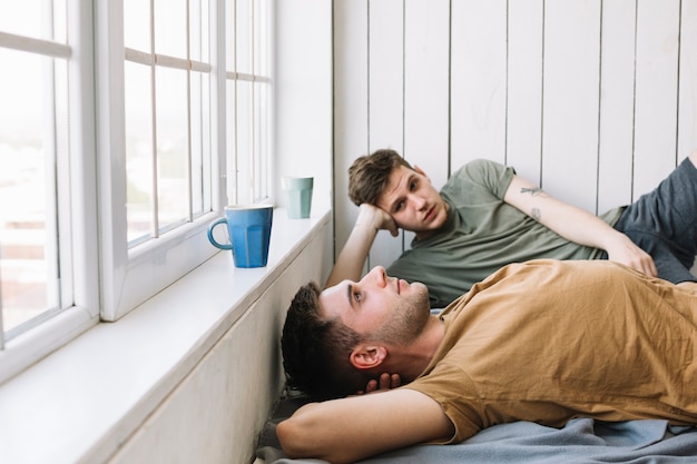 Foto gratuita dos joven descansando junto a la ventana