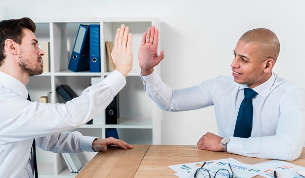 Dos joven empresario dando la alta cinco en el lugar de trabajo