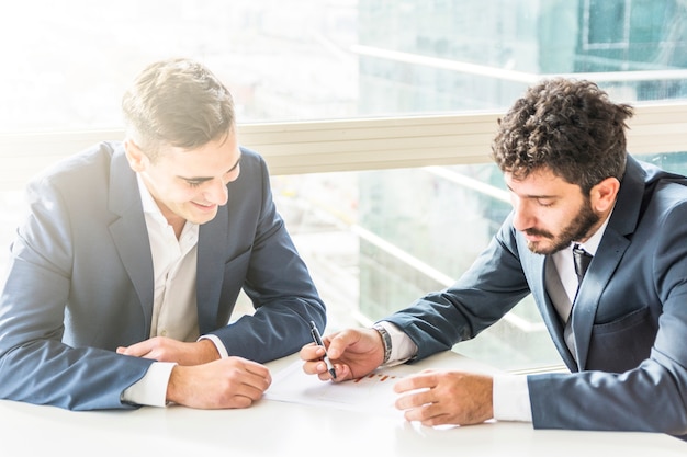 Dos joven empresario planeando el plan de negocios en el escritorio blanco