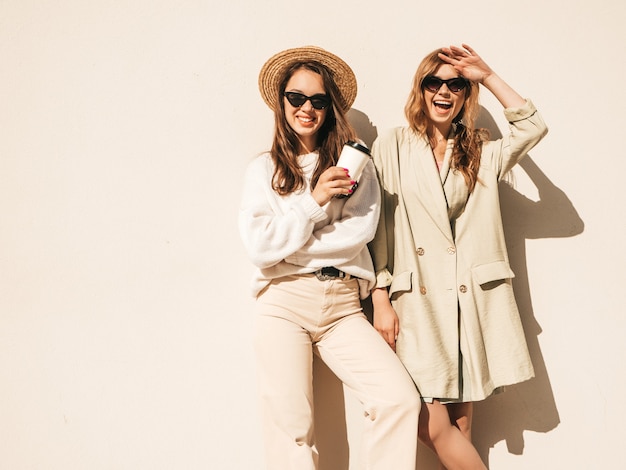 Dos joven hermosa mujer sonriente hipster en abrigo y suéter blanco de moda