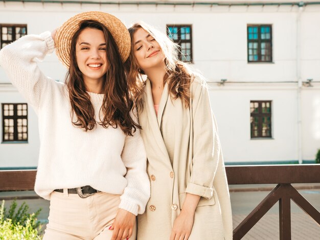 Dos joven hermosa mujer sonriente hipster en abrigo y suéter blanco de moda