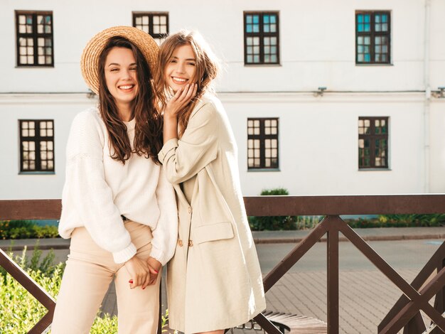 Dos joven hermosa mujer sonriente hipster en abrigo y suéter blanco de moda