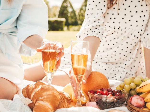 Dos joven hermosa mujer sonriente hipster en vestido de verano y sombreros. Mujeres despreocupadas haciendo picnic afuera.