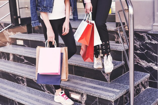 Dos joven llevando bolsas de compras mientras camina por las escaleras después de visitar las tiendas.