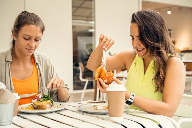 Dos jóvenes amigas hermosas desayunan juntas, brunch amistoso.