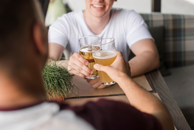 Foto gratuita dos jóvenes amigos brindando vasos de cerveza