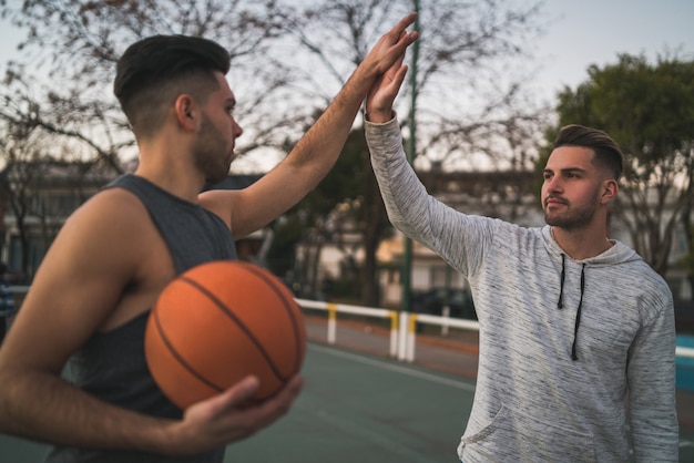 Dos jóvenes amigos jugando baloncesto.