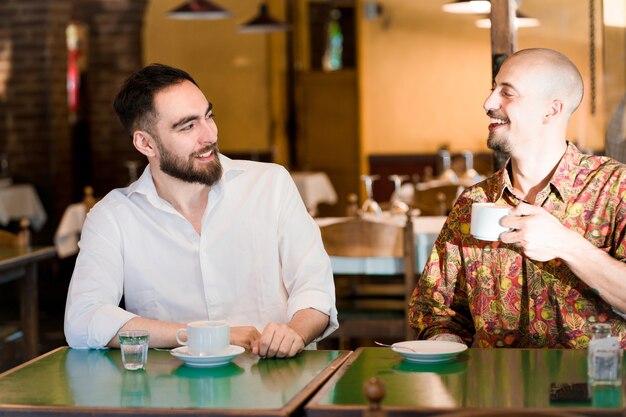 Dos jóvenes amigos pasar tiempo juntos mientras beben una taza de café en una cafetería.