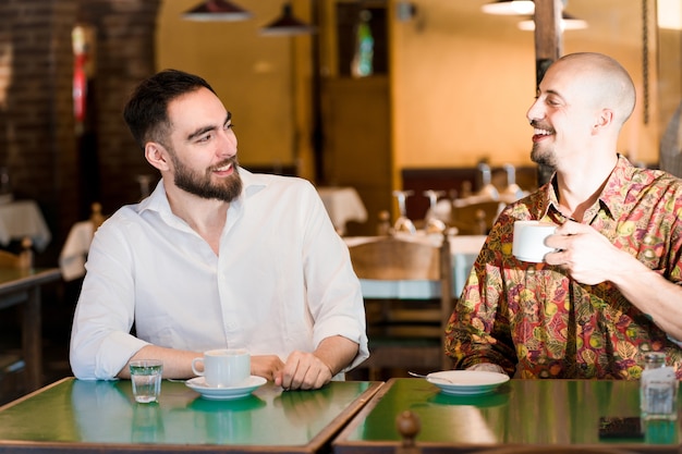 Dos jóvenes amigos pasar tiempo juntos mientras beben una taza de café en una cafetería.