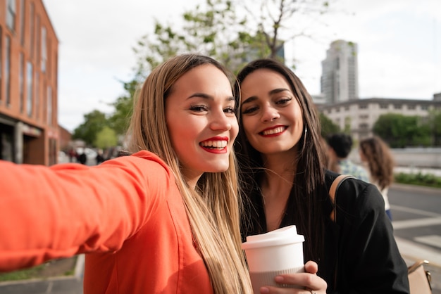 Dos jóvenes amigos tomando una selfie al aire libre.