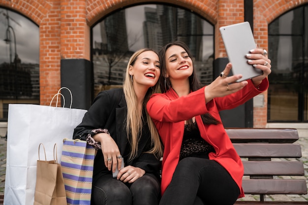 Dos jóvenes amigos tomando una selfie con tableta digital.