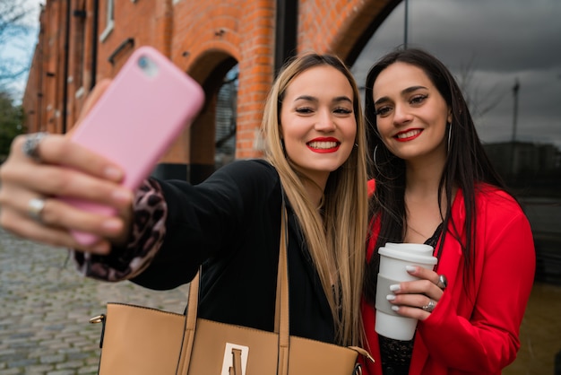 Dos jóvenes amigos tomando una selfie con teléfono móvil.