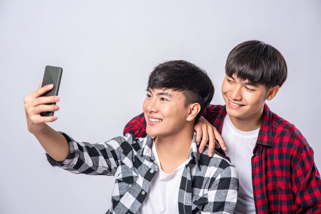 Dos jóvenes amorosos se sientan en una silla y toman una selfie desde un teléfono inteligente.