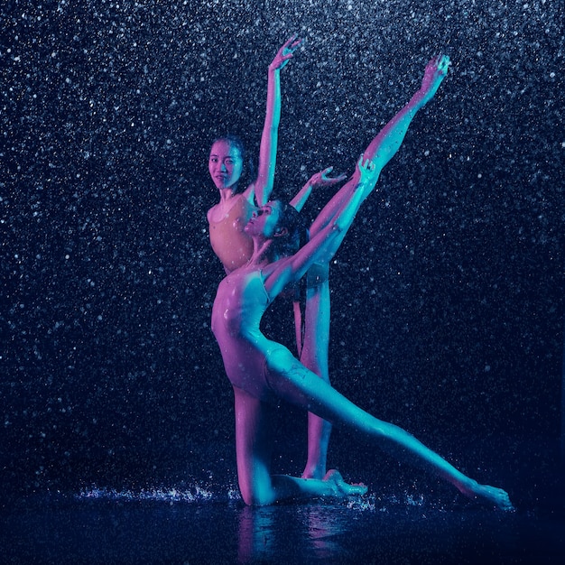 Dos jóvenes bailarinas de ballet bajo las gotas de agua