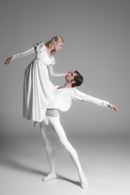 Foto gratuita dos jóvenes bailarines de ballet practicando. atractivos bailarines en blanco