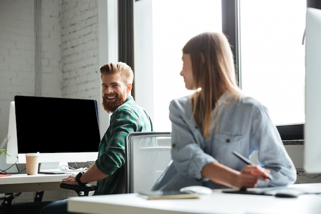 Dos jóvenes colegas felices trabajan en la oficina