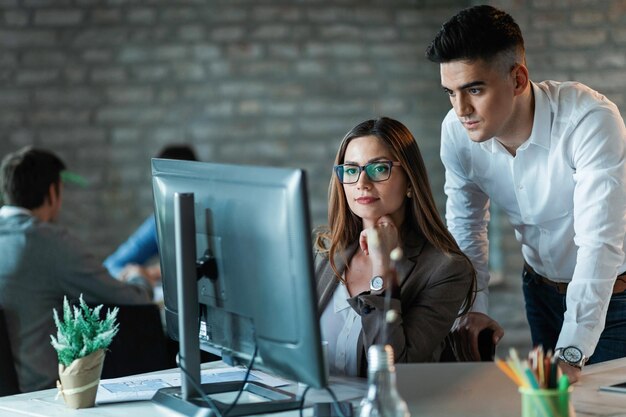 Dos jóvenes emprendedores trabajando en una computadora y leyendo un correo electrónico en la oficina