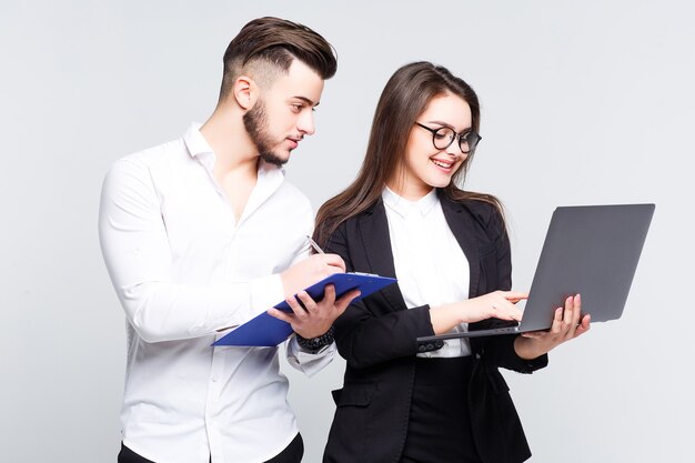 Dos jóvenes empresarios exitosos sonrientes felices que trabajan con el portátil en la pared blanca