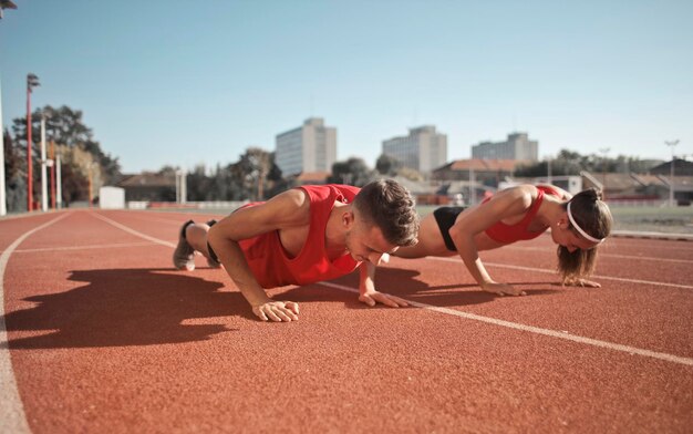 dos jóvenes hacen flexiones para entrenar en una pista