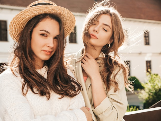 Dos jóvenes hermosas chicas hipster en abrigo y suéter blanco de moda
