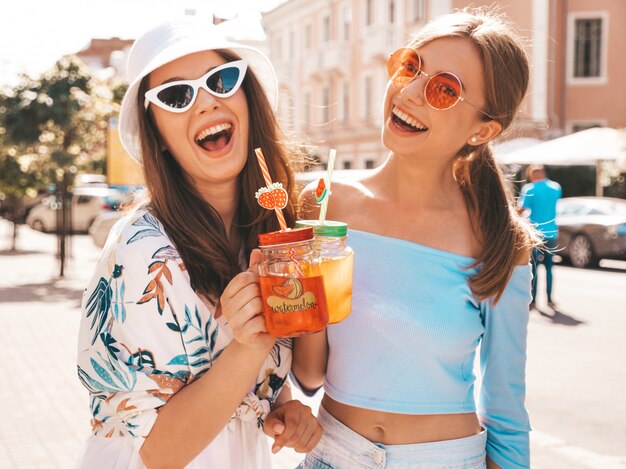 Dos jóvenes hermosas chicas hipster sonrientes en ropa de moda de verano y sombrero de Panamá.