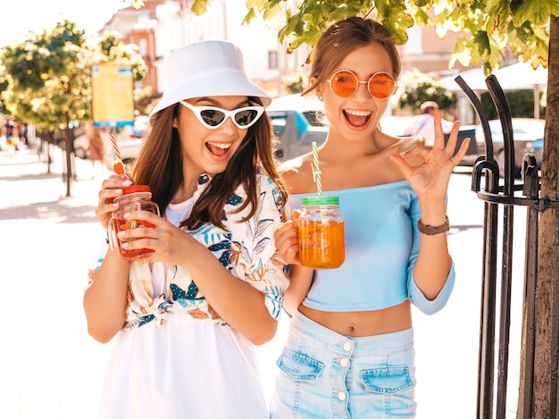 Dos jóvenes hermosas chicas hipster sonrientes en ropa de moda de verano y sombrero de Panamá.