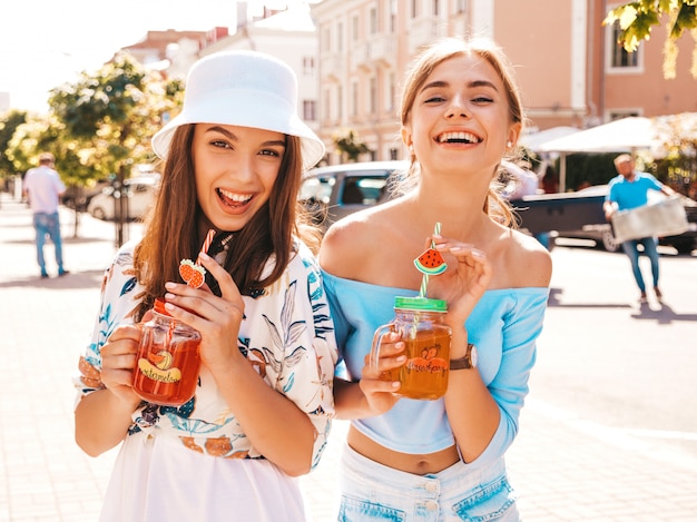 Dos jóvenes hermosas chicas hipster sonrientes en ropa de moda de verano y sombrero de panamá.