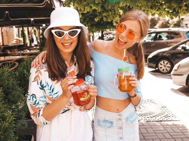 Dos jóvenes hermosas chicas hipster sonrientes en ropa de moda de verano y sombrero de Panamá.