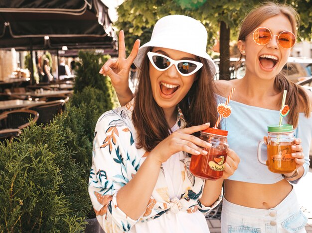 Dos jóvenes hermosas chicas hipster sonrientes en ropa de moda de verano y sombrero de Panamá.