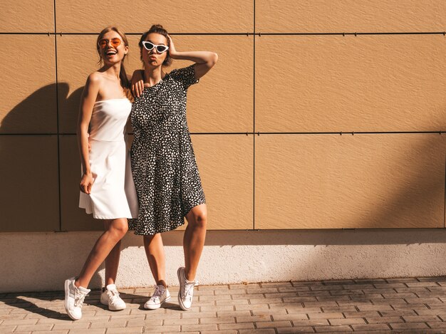 Dos jóvenes hermosas chicas hipster sonrientes en vestido de moda de verano.