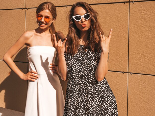 Dos jóvenes hermosas chicas hipster sonrientes en vestido de moda de verano.