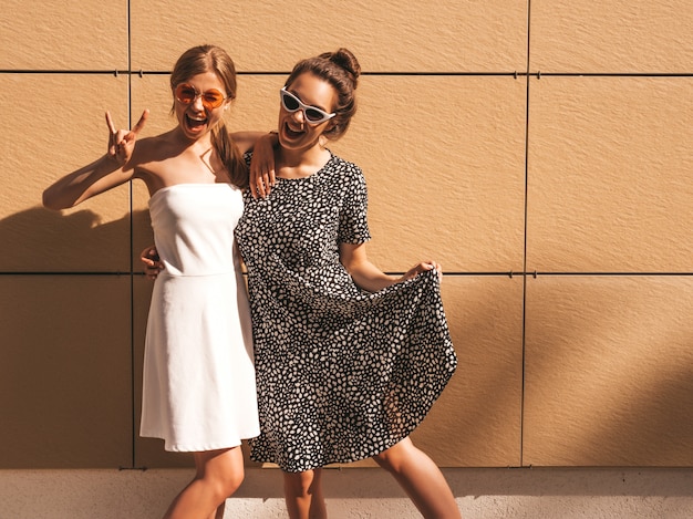 Dos jóvenes hermosas chicas hipster sonrientes en vestidos de moda de verano.