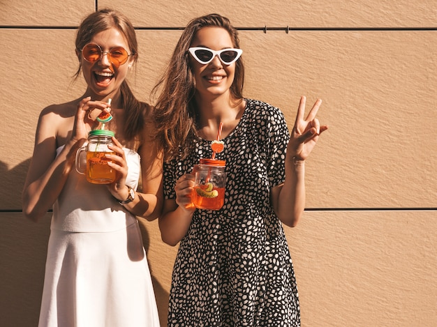 Dos jóvenes hermosas chicas hipster sonrientes en vestidos de moda de verano.