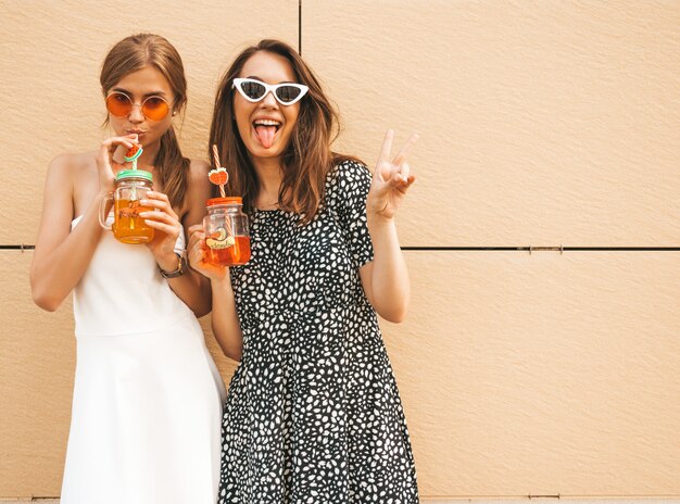 Dos jóvenes hermosas chicas hipster sonrientes en vestidos de moda de verano.