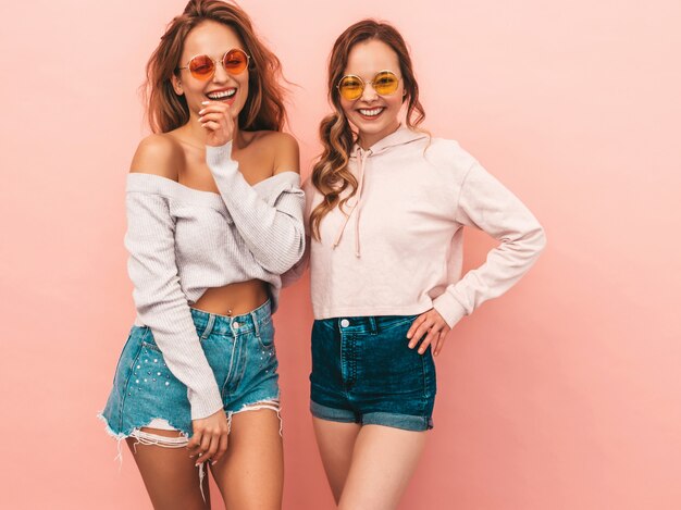 Dos jóvenes hermosas chicas sonrientes en ropa de moda de verano. Sexy mujer despreocupada posando. Modelos positivos divirtiéndose