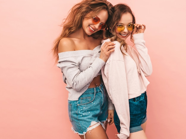 Foto gratuita dos jóvenes hermosas chicas sonrientes en ropa de moda de verano. sexy mujer despreocupada posando. modelos positivos divirtiéndose