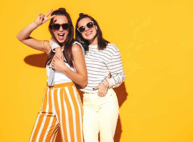 Dos jóvenes hermosas mujeres hipster rubias sonrientes en ropa de verano de moda Mujeres sexy despreocupadas posando en el estudio Modelos positivos divirtiéndose Alegre y feliz