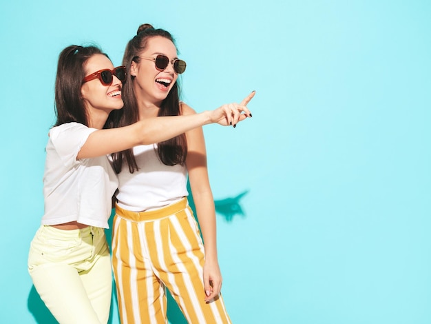 Dos jóvenes hermosas mujeres hipster rubias sonrientes en ropa de verano de moda Mujeres sexy despreocupadas posando en el estudio Modelos positivos divirtiéndose Alegre y feliz