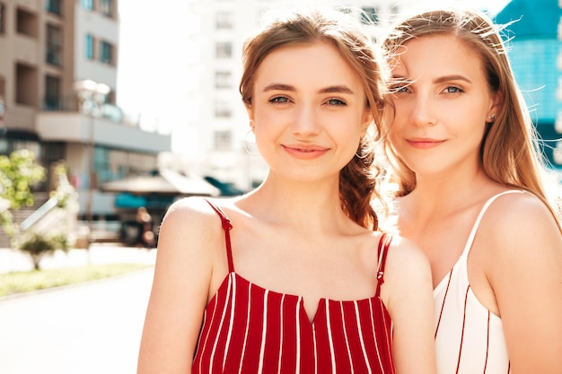 Dos jóvenes hermosas mujeres hipster sonrientes en overoles de moda Mujeres sexy despreocupadas posando en el fondo de la calle Modelos positivos divirtiéndose abrazándose y volviéndose loco Concepto de belleza