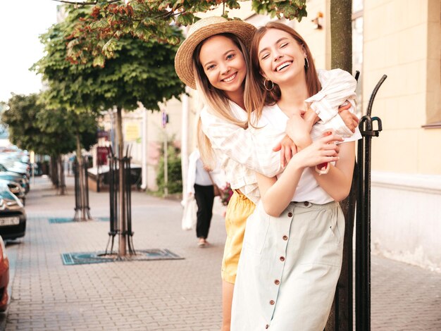 Dos jóvenes hermosas mujeres hipster sonrientes con ropa de verano de moda. Mujeres sexy y despreocupadas posando en la calle. Modelos puros positivos divirtiéndose al atardecer abrazándose y volviéndose locos. Alegre y feliz.