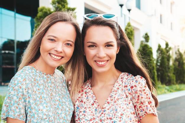 Dos jóvenes hermosas mujeres hipster sonrientes en vestidos de verano de moda Mujeres sexy despreocupadas posando en la calle Modelos puros positivos divirtiéndose al atardecer abrazándose y volviéndose locos